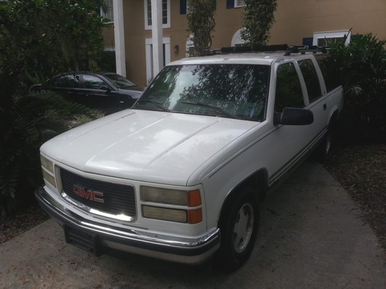 Dale Novak's white 1999 Suburban SUV with a roof rack, parked on a concrete driveway