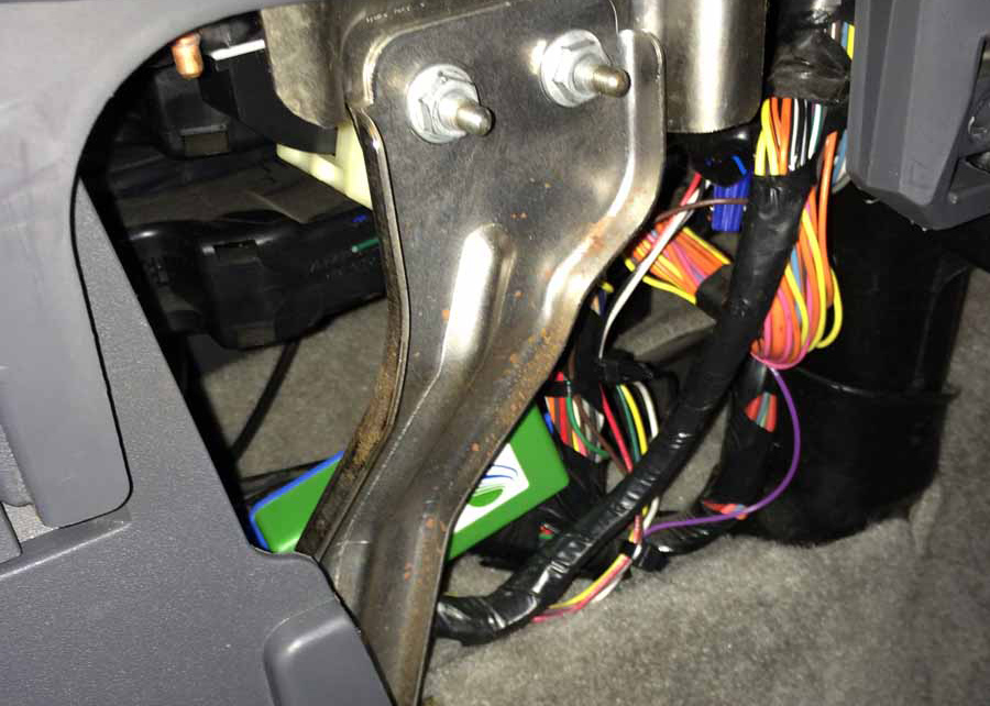 Underneath the dashboard of a 2004 Saturn Ion showing the wiring harness and NEWROCKIES PRO Module near the Body Control Module during installation
