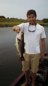 Linc Thomas smiling and holding a large bass he caught after his 1999 GMC 1500 was fixed
