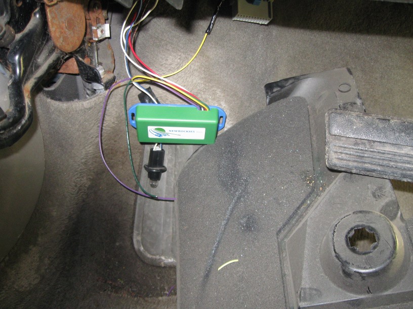 The NEWROCKIES PRO Module installed in a vehicle footwell on the gray carpet