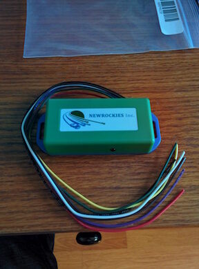 The green NEWROCKIES PRO Module with wires attached on a wooden workbench