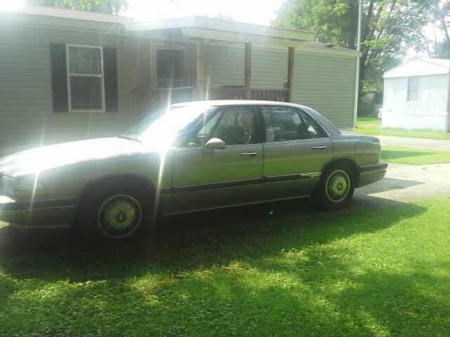 Cassandra's silver Buick LeSabre parked on the grass in front of the house