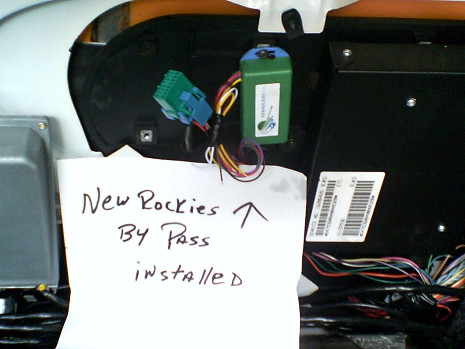 The green NEWROCKIES PRO Module installed under the dash with a handwritten note and arrow reading "New Rockies By Pass installed"