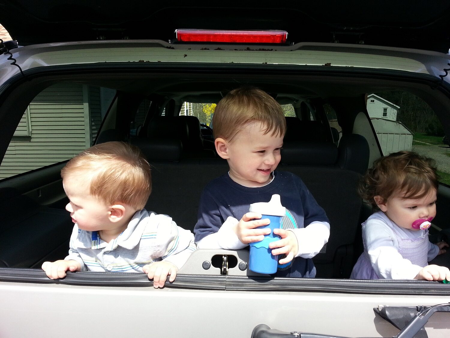 Three young children sitting in the open back of the Yukon XL
