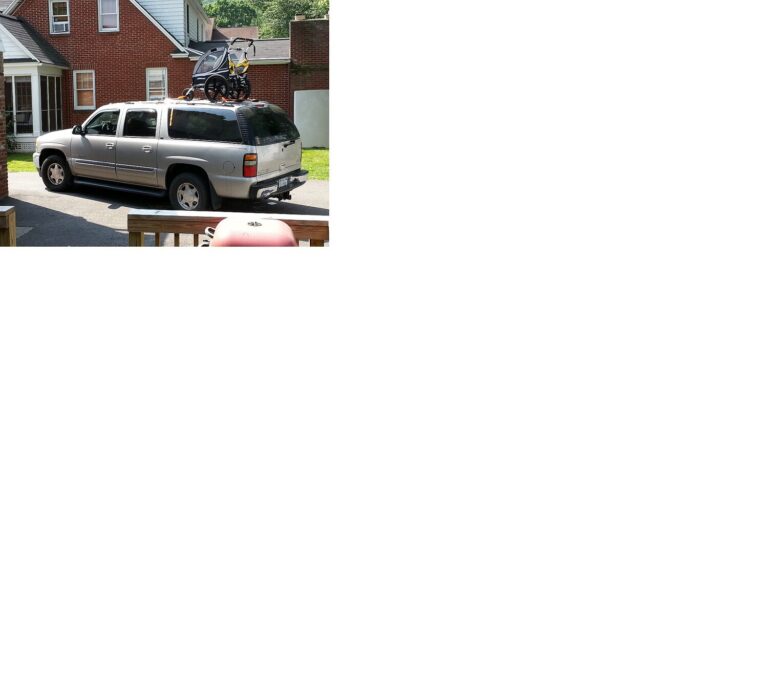 The silver Yukon XL in the driveway with a child's bike trailer on the roof