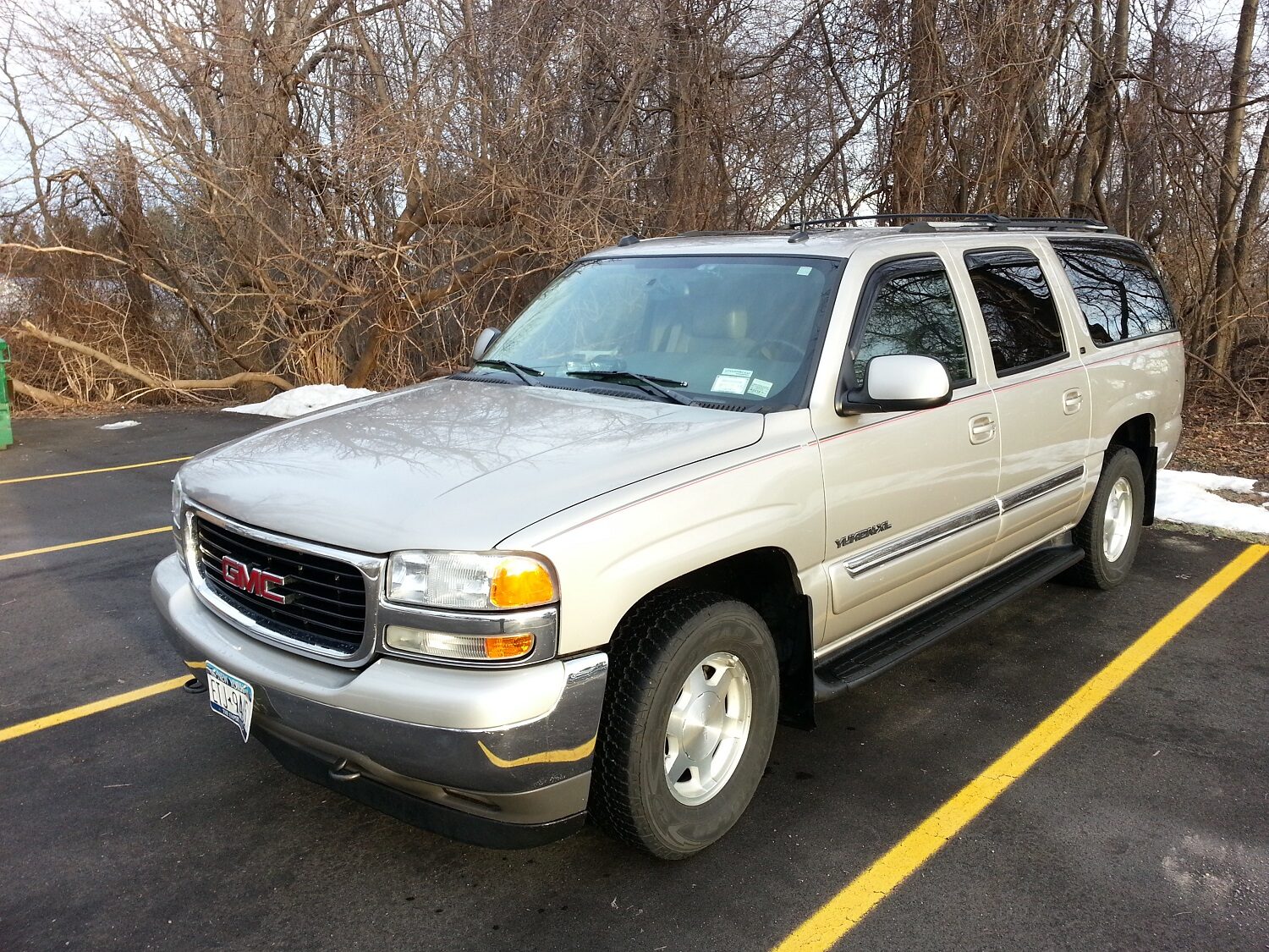 The GMC Yukon XL parked in a parking lot near bare trees