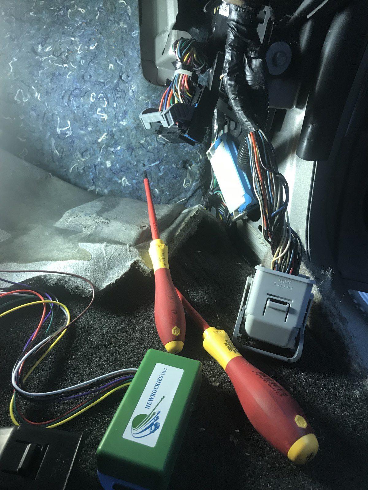Exposed Hummer H3 wiring with insulated screwdrivers and the green PRO Module on the floor