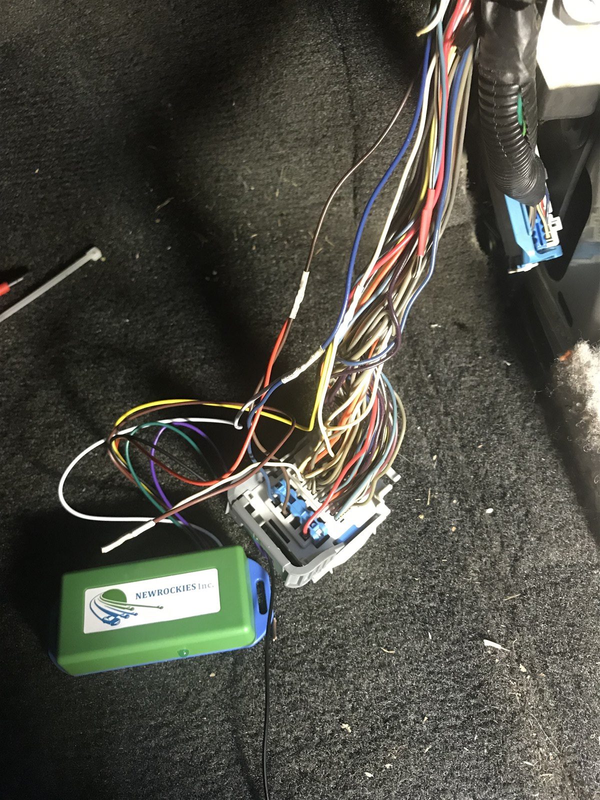 Green NEWROCKIES module spliced into the Hummer H3 wiring bundle on dark carpet
