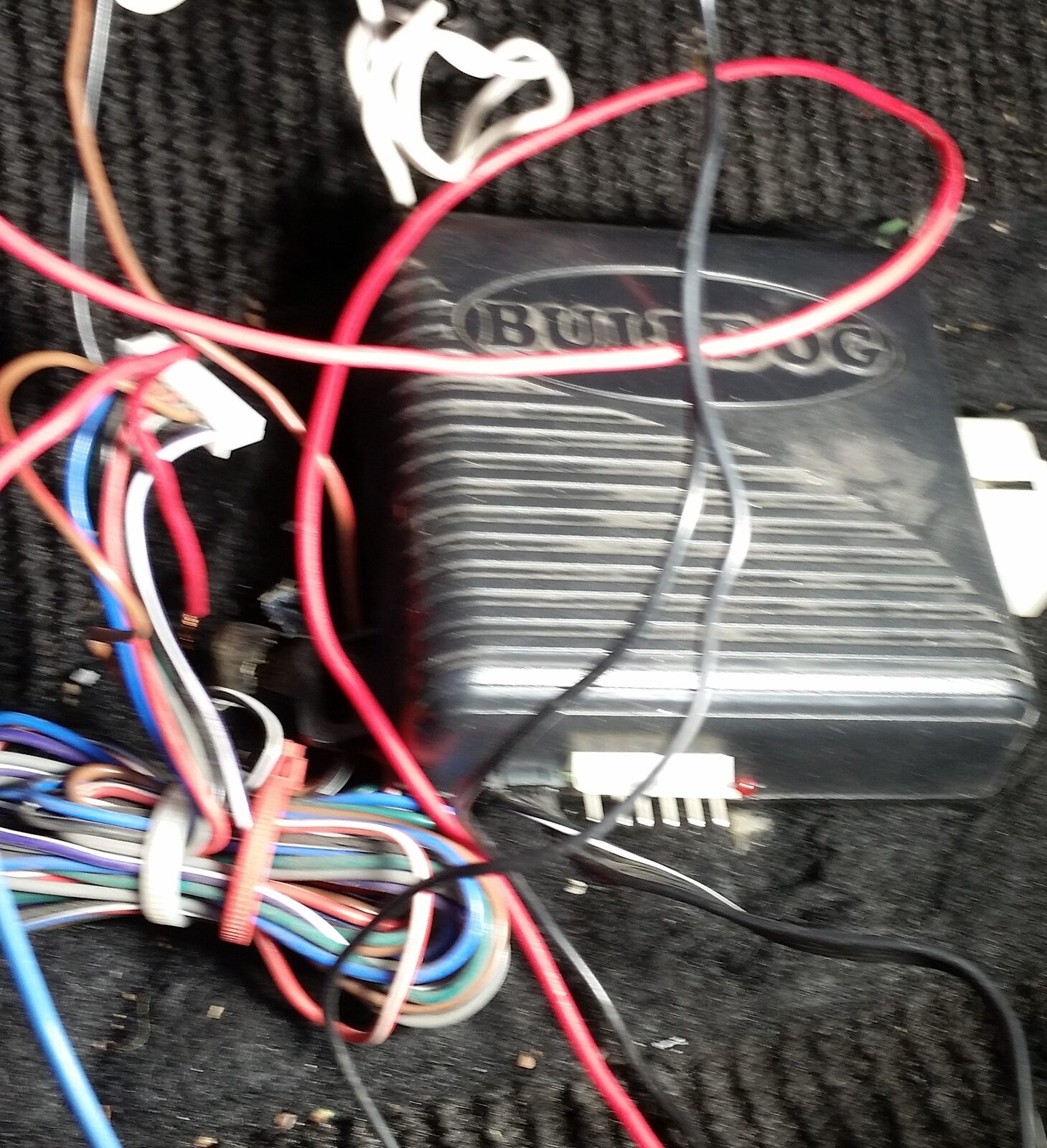 The failed aftermarket remote start unit connected to a bundle of spliced multi-coloured wires