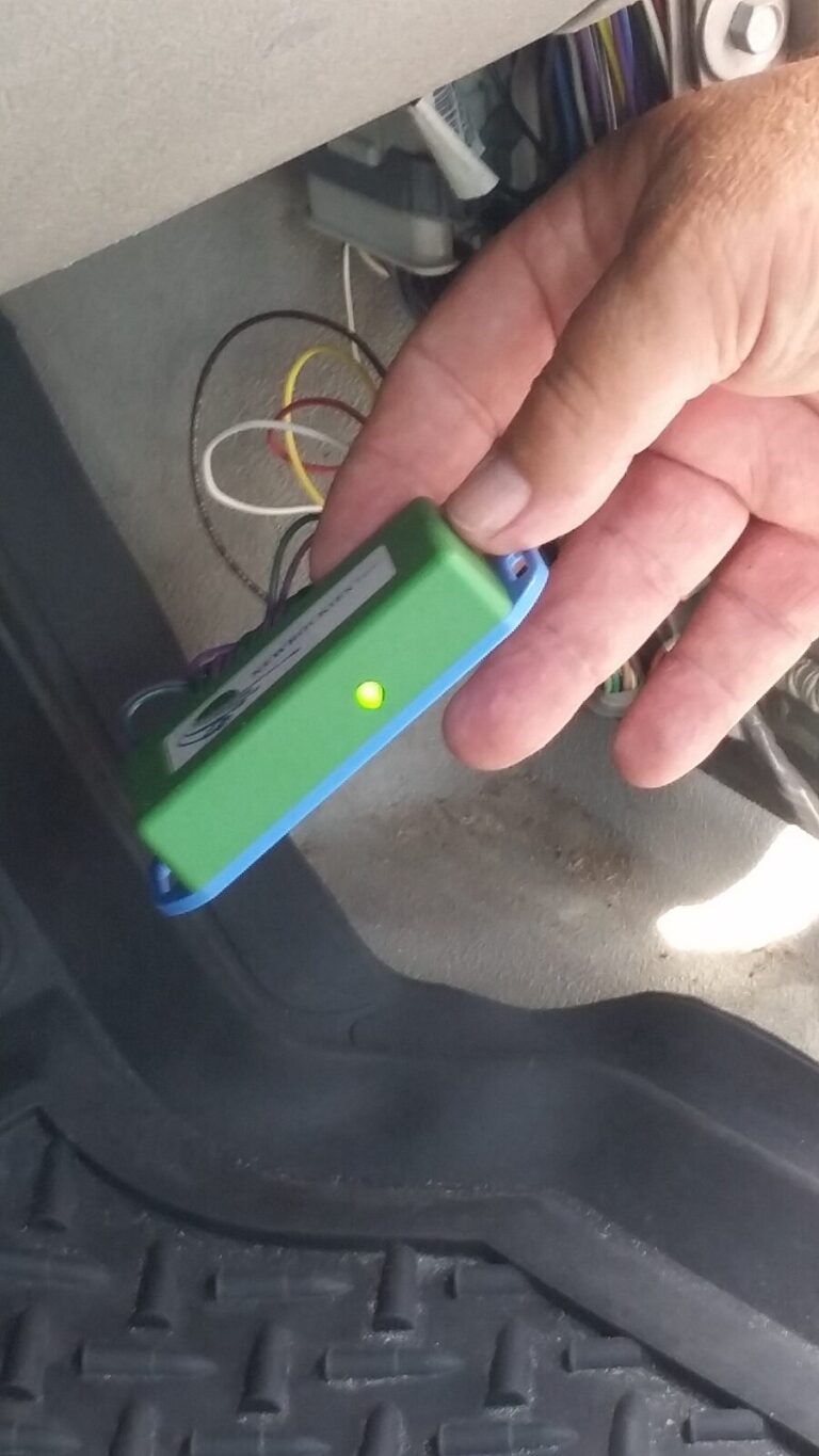 A hand holding the green NEWROCKIES PRO Module with its green LED lit in George's Canyon