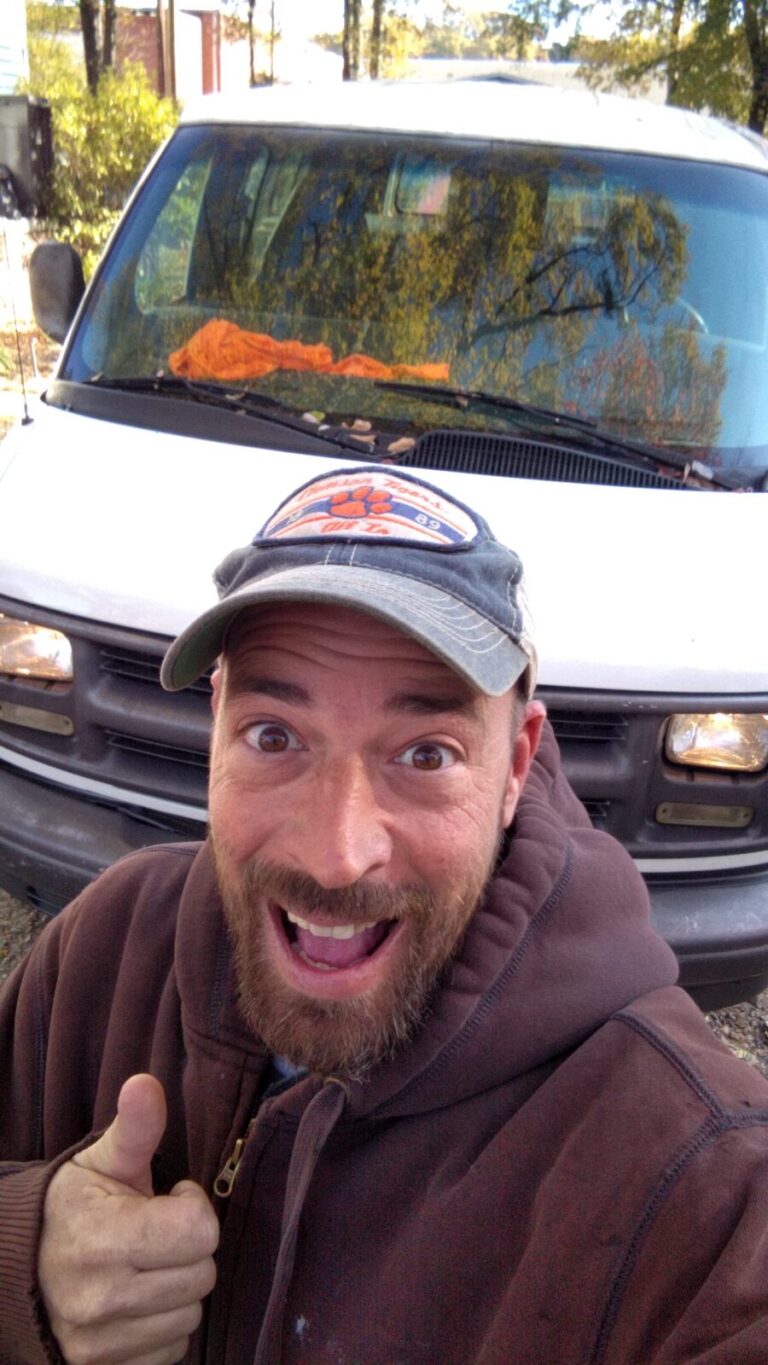 Joseph giving a thumbs-up in front of his white 1998 Chevy Express van
