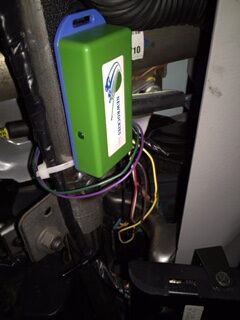 The green NEWROCKIES module zip-tied and wired to the Suburban steering column