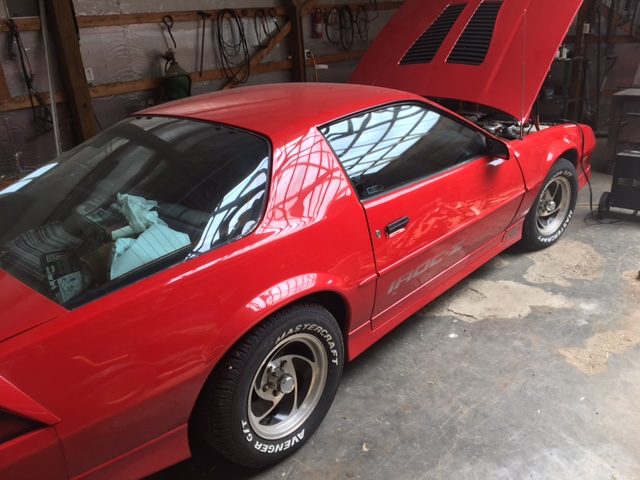 Red 1989 Chevrolet Camaro IROC with the hood open in a garage