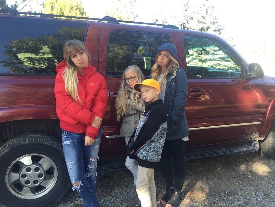 Family standing beside their dark red 2003 Chevrolet Suburban during the no-start period