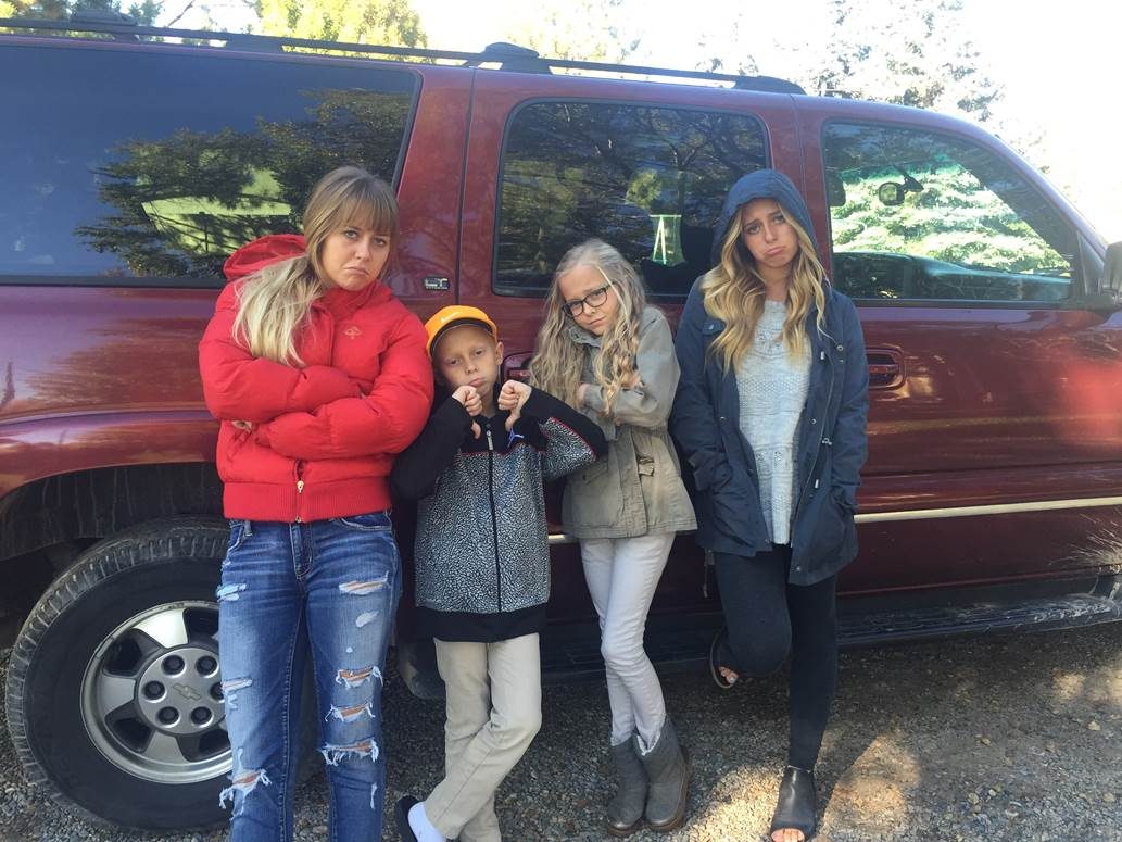 Family pulling frowning faces beside the maroon Suburban that would not start