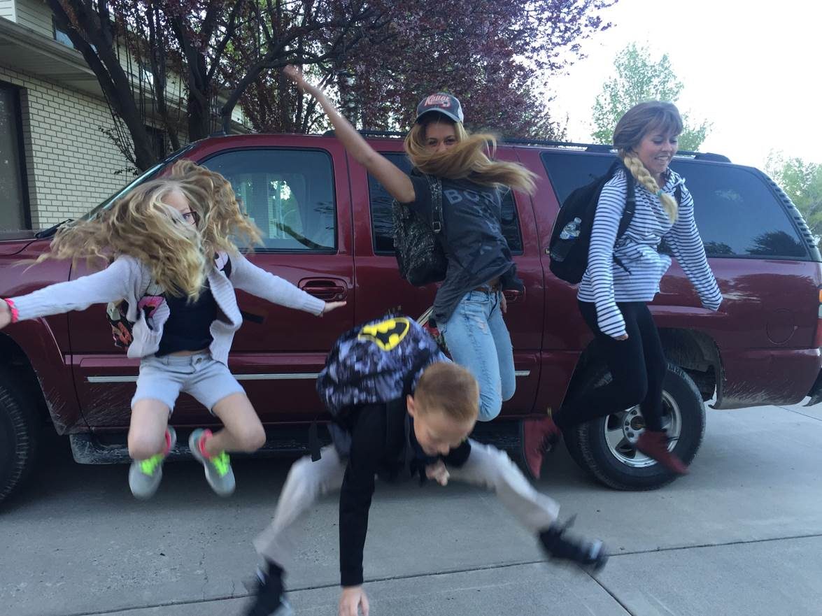 Family jumping in the air with school backpacks in front of the Suburban that now starts every time